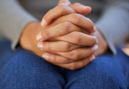 Woman, hands together and nervous depression, anxiety and mental health in psychology counselling therapy or praying to god. Zoom, prayer fingers and person with stress in counseling help and worship.